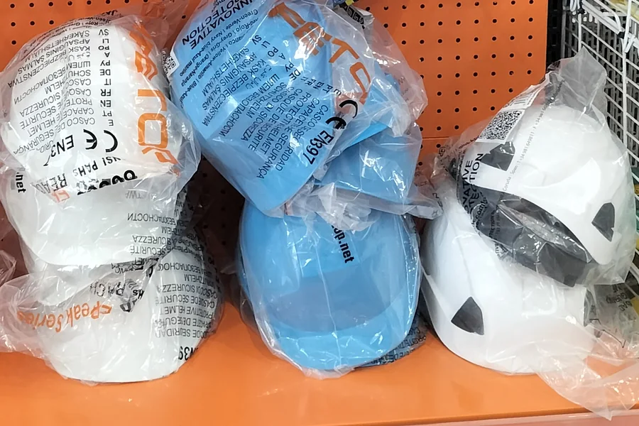 Cascos de obra blancos y azules en su bolsa, en el expositor de la tienda